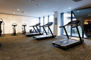 Ein Fitnessstudio mit Laufbändern, Ergometer und einem Rudergerät.