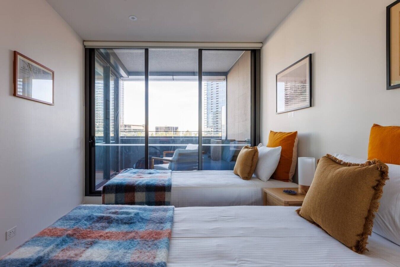 Quarto de hotel com duas camas, varanda e uma janela grande.