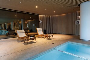 Uma área à beira da piscina com espreguiçadeiras e piscina.