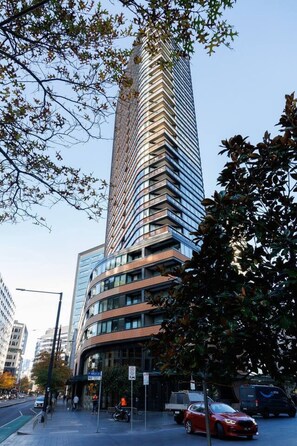 Ein modernes Hochhaus mit geschwungener Fassade, umgeben von Stadtstraßen und parkenden Autos.
