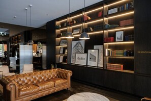 A modern interior with a leather sofa, bookshelves, and framed pictures. - Indi | Chic Inner-City Retreat with Parking (Collingwood)