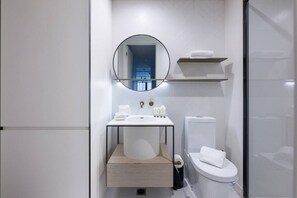 Ein modernes Badezimmer mit einem weißen Waschbecken, einer Toilette und einem Spiegel über dem Waschbecken.