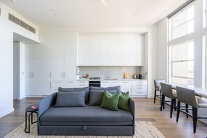 Un salon moderne avec un canapé gris foncé, une petite table d’appoint et un coin repas comprenant une longue table et des chaises.