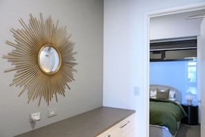 A bedroom with a bed, bedside table, and a wall-mounted mirror with a sunburst design. - Herald Living - Iconic City Heritage Building (Melbourne)