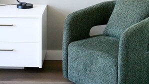A room with a white nightstand, a black desk lamp, a green armchair, and a colorful abstract painting on the wall. - Herald Living - Iconic City Heritage Building (Melbourne)