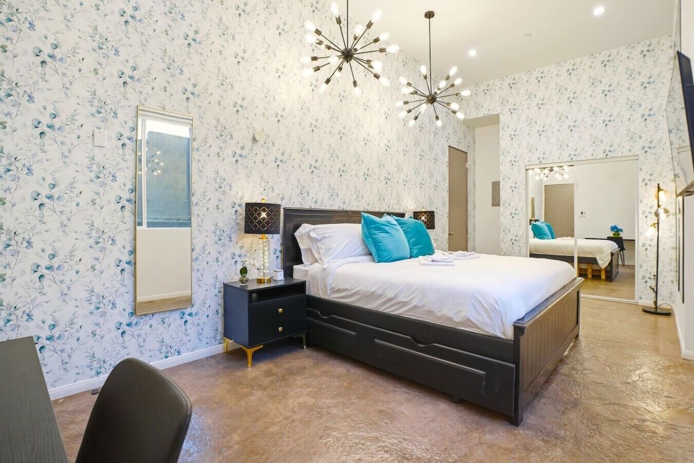 A bedroom with a bed, nightstand, lamp, and a mirror.