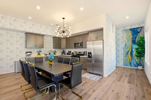 A modern kitchen with a dining area, featuring a central island, stainless steel appliances, and a decorative painting.