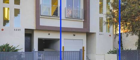 A two-story residential building with a garage, numbered 5239 and 5241, featuring a modern design with a balcony and a staircase.