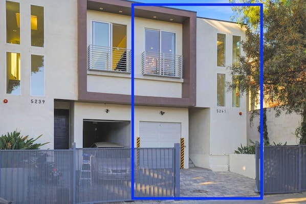 A two-story residential building with a garage, numbered 5239 and 5241, featuring a modern design with a balcony and a staircase.