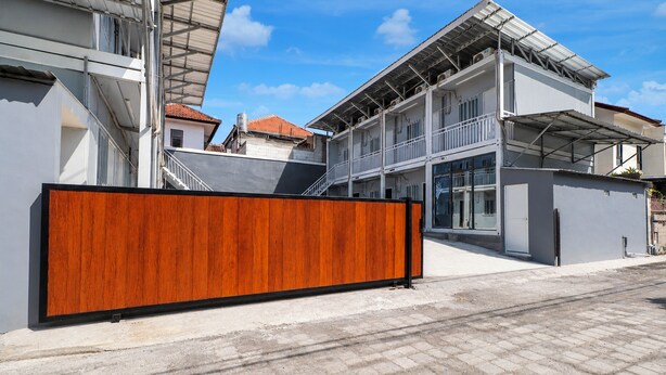 A modern building with a large wooden fence in front, a staircase leading to an upper level, and a clear sky. - Hotel O near Living Word Mall formerly T (Denpasar)