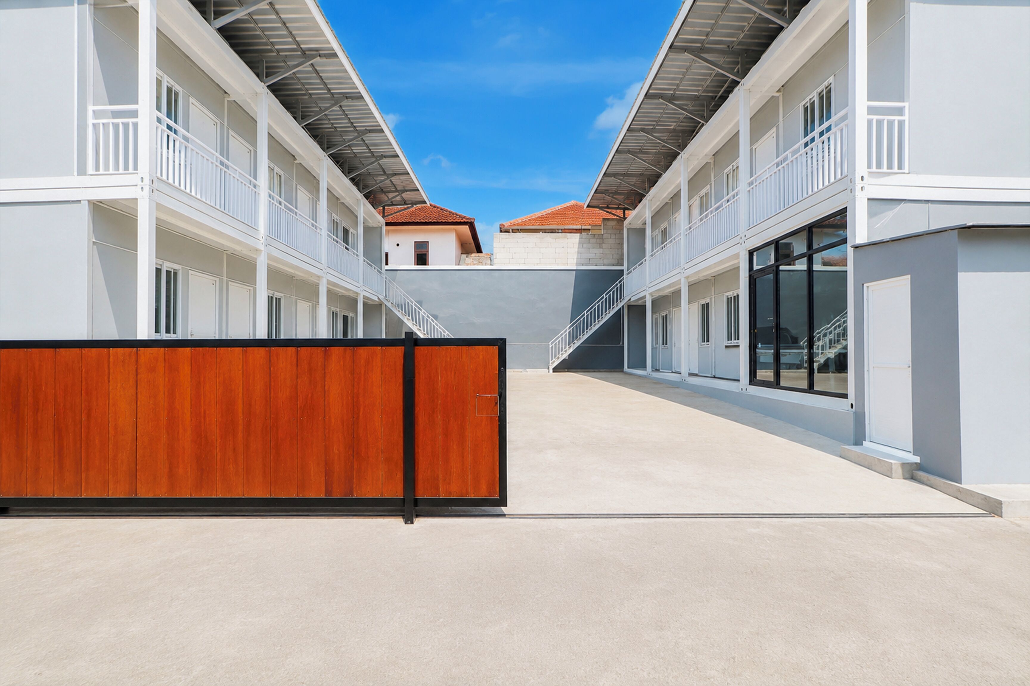 Un edificio moderno con un patio central, cerca de una valla de madera y un cielo despejado.