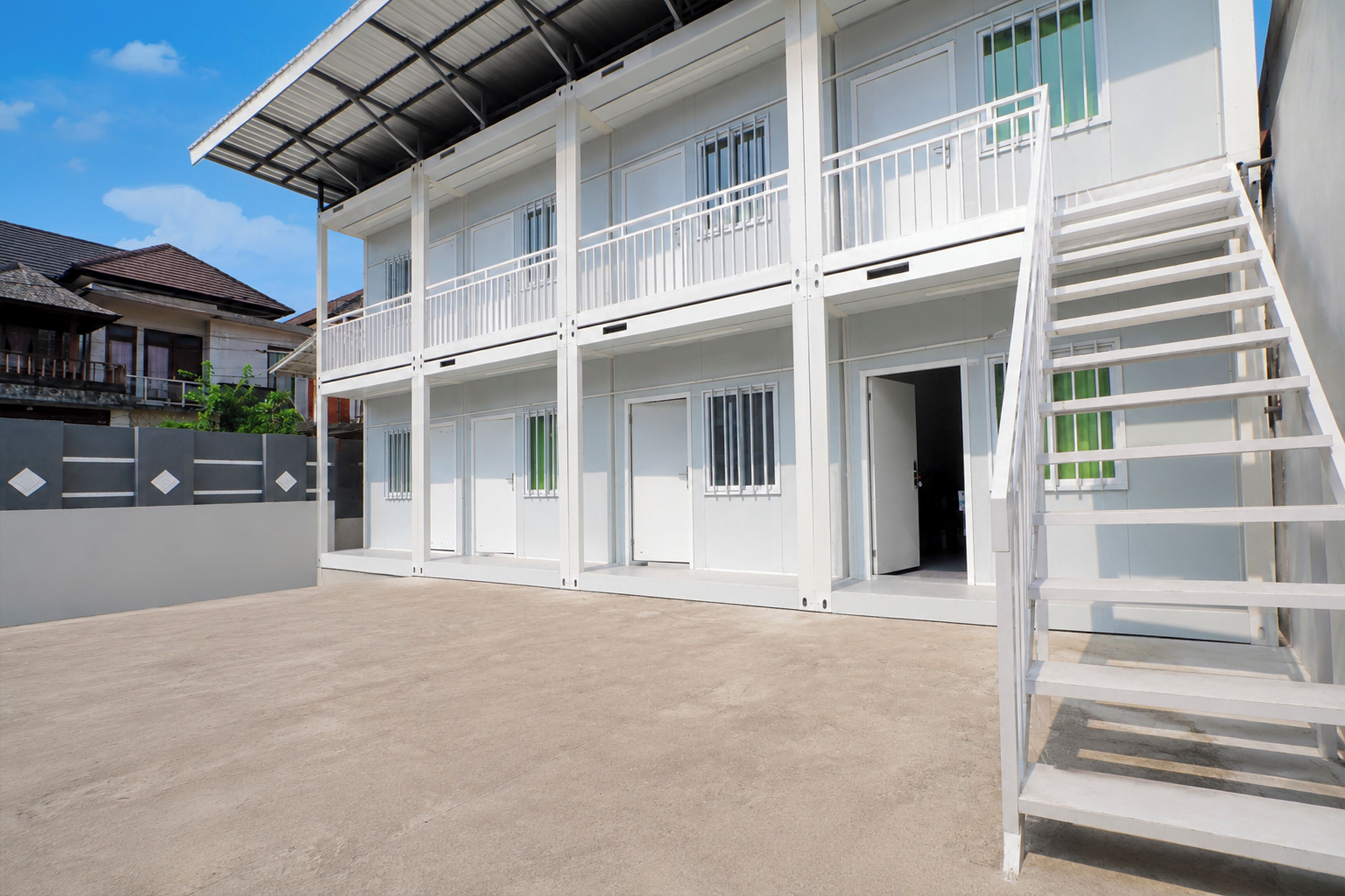 A multi-story building with a flat roof, balconies, and a staircase.