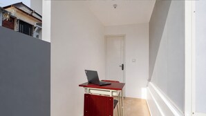 A narrow corridor with a door at the end, a red table with a laptop, and a white wall. - Hotel O near Living Word Mall formerly T (Denpasar)
