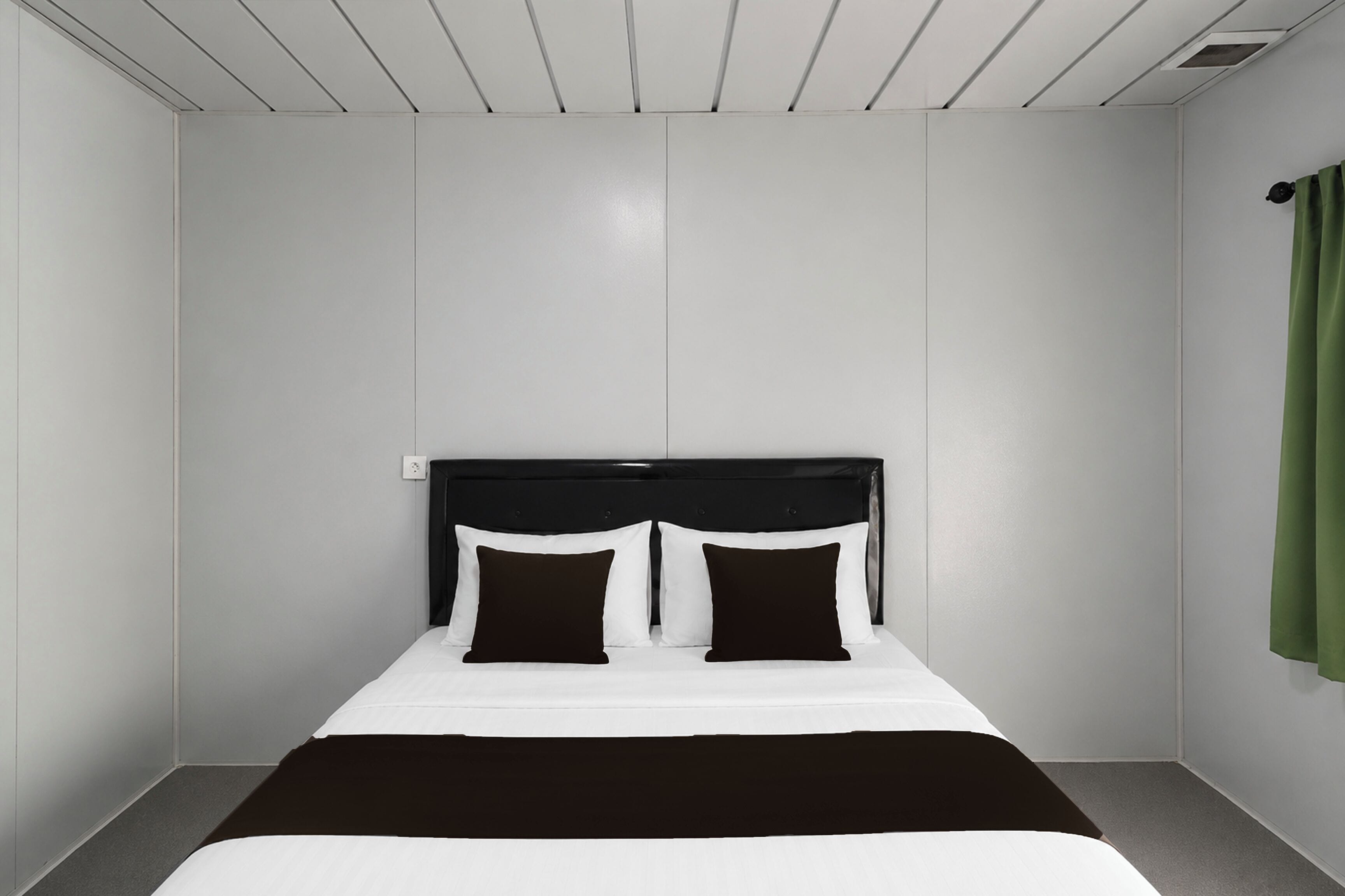 A hotel room with a bed, a headboard, and a green curtain.