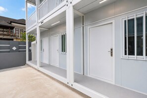 Un immeuble à plusieurs étages, doté d’un balcon à l’étage supérieur, d’une série de portes et d’un rez-de-chaussée en béton.