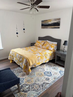 Une chambre à coucher avec un lit, une table de chevet, une lampe et un ventilateur de plafond.