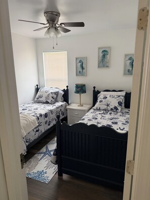 A bedroom with two single beds, a ceiling fan, and three seahorse wall art pieces. - Awesome 3-bedroom house in charming downtown Wilmington. Minutes from River Walk (Wilmington)