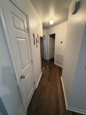 Un couloir doté d’un plancher en bois, de murs blancs et d’une porte blanche avec une poignée de porte en laiton.