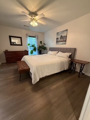A bedroom with a bed, a ceiling fan, a window with curtains, a dresser, a plant, and a painting on the wall. - Cozy & eclectic 1BR guest house w/ private entrance & full kitchen. Pet friendly (Lexington)