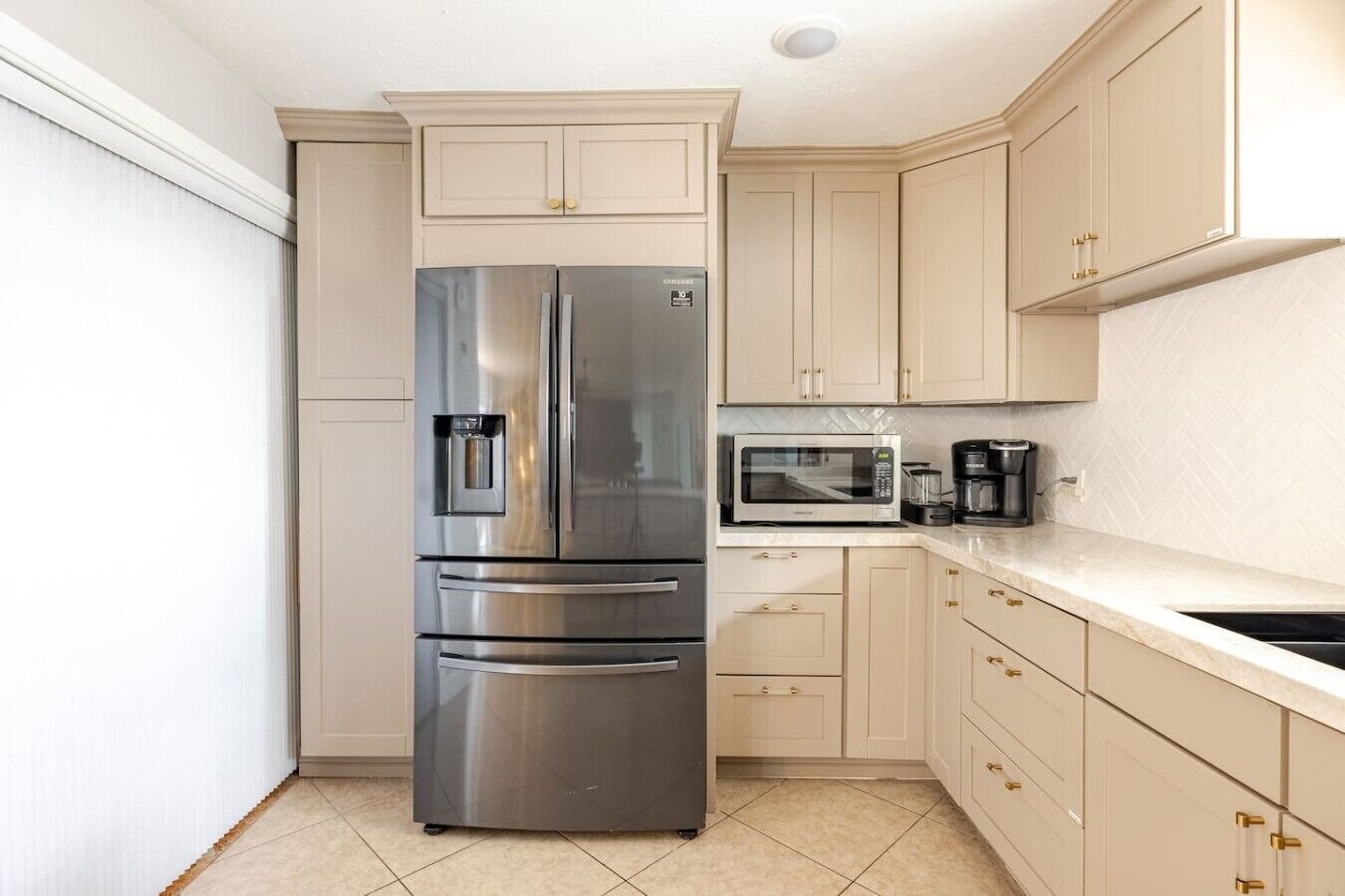 A compact kitchen with a stainless steel refrigerator, a microwave, and a coffee maker.