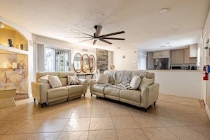 A living room with two sofas, a ceiling fan, and a kitchen in the background. - The Phoenix Haven Resort Village | Pool & Gym | (Phoenix)