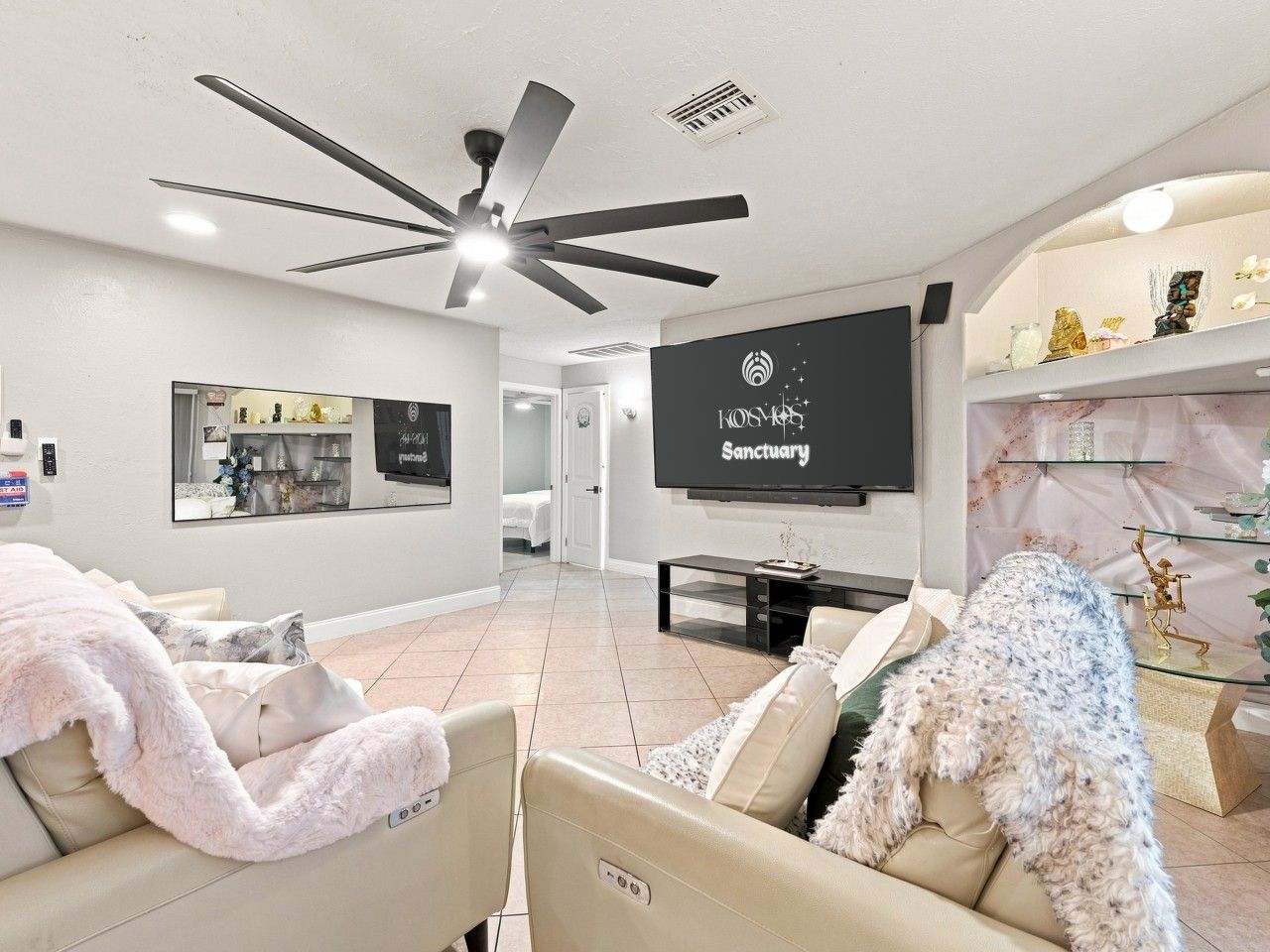 Un salon moderne doté d’un ventilateur de plafond, d’un téléviseur à écran plat et d’un canapé agrémenté d’un plaid moelleux.