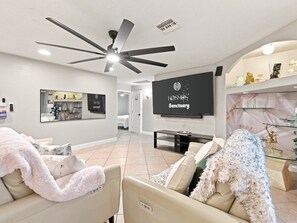 A modern living room with a ceiling fan, a flat-screen TV, and a sofa with a fluffy throw blanket. - The Phoenix Haven Resort Village | Pool & Gym | (Phoenix)