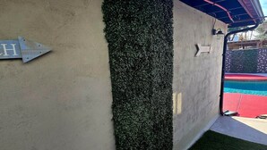 Eine Wand mit einem vertikalen Garten und einem Metallschild mit einem Buchstaben.