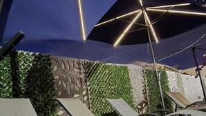 Liegestühle und Sonnenschirme im Freien, die eine Terrasse oder einen Außenbereich zum Sitzen andeuten.