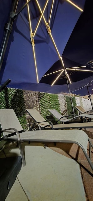 Outdoor lounge chairs and umbrellas, suggesting a patio or outdoor seating area. - The Phoenix Haven Resort Village | Pool & Gym | (Phoenix)
