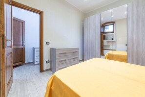 A bedroom with a bed, a dresser, a wardrobe, and a door leading to another room. - Casa Roberta - Goelba (Portoferraio)
