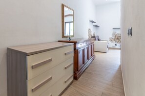 A modern interior with a wooden cabinet, a mirror, a white sofa, and a stone wall. - Casa Roberta - Goelba (Portoferraio)