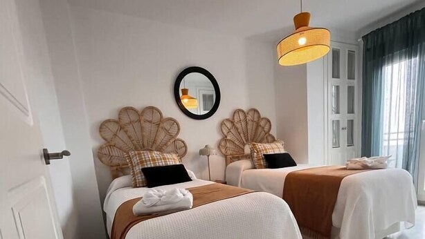 Een slaapkamer met twee bedden, een spiegel en een hanglamp.