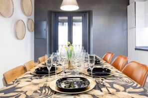 A dining area with a table set for six, surrounded by chairs, with a window and wall decor visible. - Impresionante duplex con terraza propia Sevilla (Sevilla)