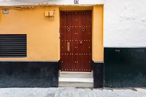 A building entrance with a wooden door, a small set of steps, and a number '15' above the door. - Impresionante duplex con terraza propia Sevilla (Sevilla)