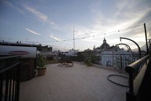 A rooftop terrace with potted plants, seating, and a view of a historic building. - Impresionante duplex con terraza propia Sevilla (Sevilla)