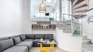 Een moderne woonkamer met een hoekbank, een glazen salontafel en een trap met een leuning.