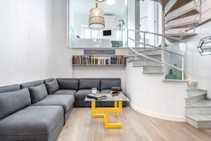 A modern living room with a sectional sofa, a glass coffee table, and a staircase with a railing. - Impresionante duplex con terraza propia Sevilla (Sevilla)