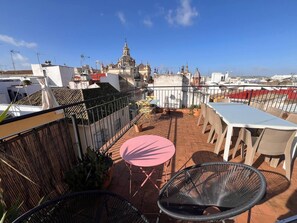 A rooftop terrace with a table and chairs, a view of a church, and a cityscape in the background. - Impresionante duplex con terraza propia Sevilla (Sevilla)