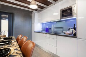 A modern kitchen with white cabinets, a built-in microwave, and a stainless steel countertop. - Impresionante duplex con terraza propia Sevilla (Sevilla)
