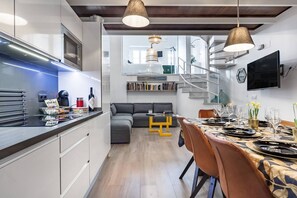 Eine moderne Küche mit Einbauofen und Mikrowelle, eine Essecke mit Tisch für sechs Personen und eine Treppe, die zu einer oberen Ebene führt.