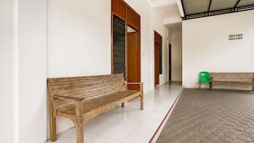 Un corridoio con due panche in legno, pavimento piastrellato di bianco e una sezione del pavimento con motivo esagonale.