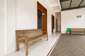 Un pasillo con dos bancos de madera, suelo de baldosas blancas y una sección de suelo con diseño hexagonal.