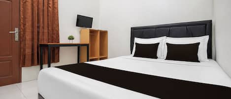 A hotel room with a bed, a desk, a television, and a window with curtains.