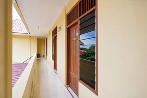 A corridor with a tiled floor, a railing, and a door with a window.
