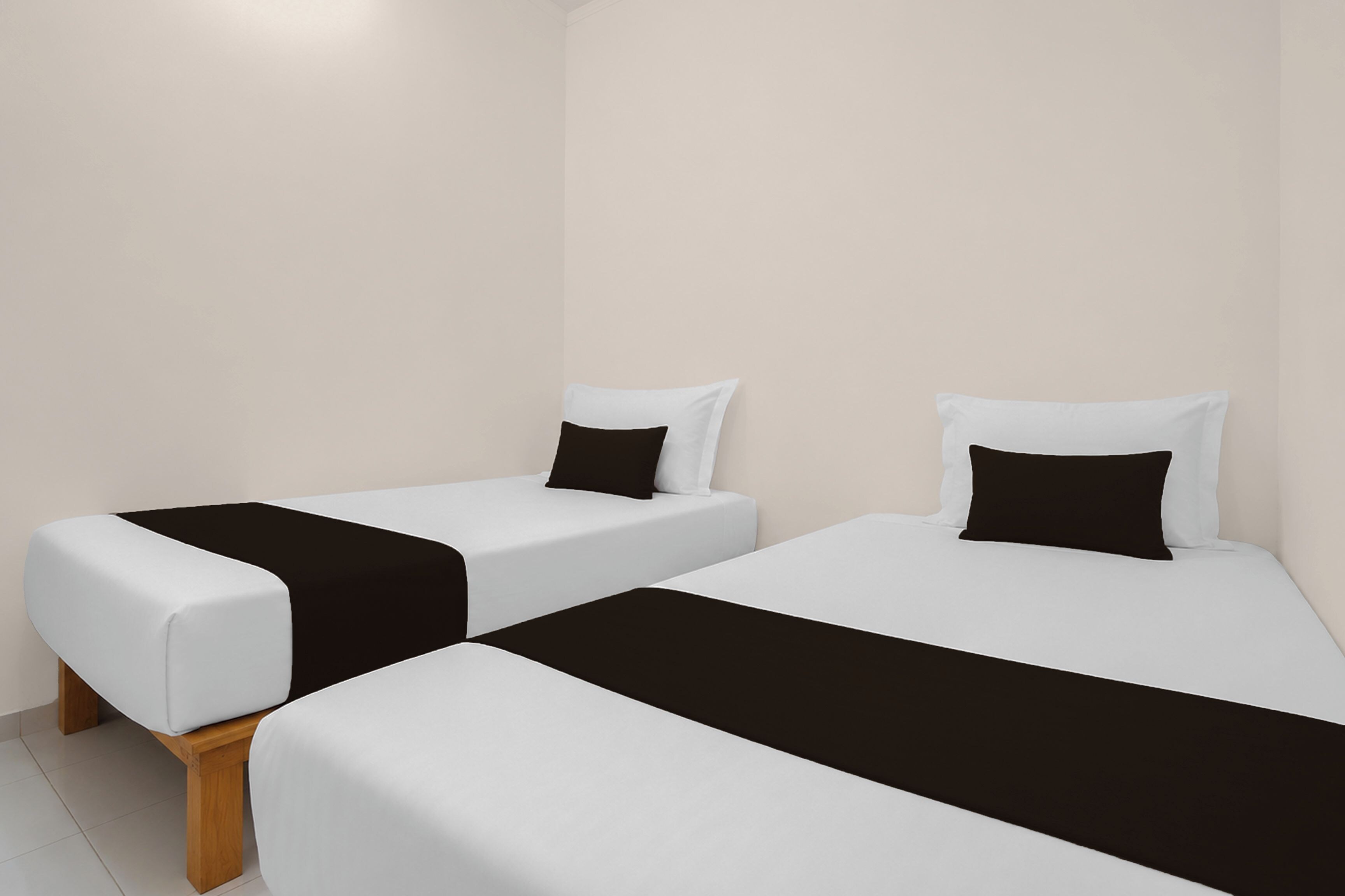 Two single beds with black and white bedding, wooden legs, and a plain wall in the background.