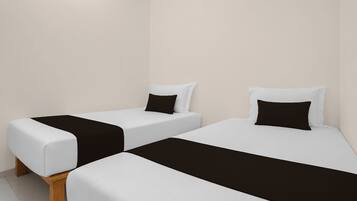 Dos camas individuales con ropa de cama blanco y negro, patas de madera y una pared lisa al fondo.