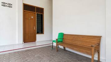 Un pasillo con un banco de madera, una silla verde y una puerta con ventanal.