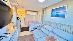 Ein Schlafzimmer mit einem Bett, einem Schlafsofa, einem Schreibtisch mit Lampe, einer Kommode und einem Bild an der Wand.