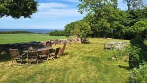 An outdoor dining area with a stone wall, wooden table, and chairs. - Cosy holiday apartment on Bornholm (Hollændergårde)